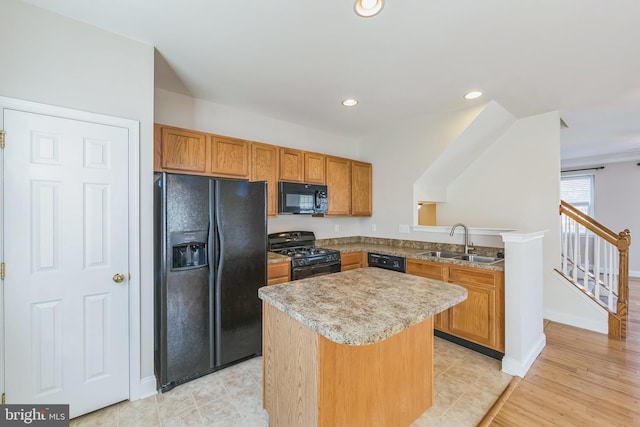 kitchen featuring sink, a center island, light hardwood / wood-style flooring, kitchen peninsula, and black appliances