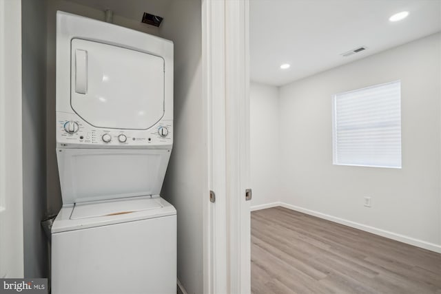 washroom featuring light hardwood / wood-style floors and stacked washer and clothes dryer