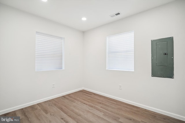 unfurnished room with electric panel and light hardwood / wood-style flooring