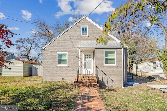 bungalow-style home with a front lawn and a storage unit