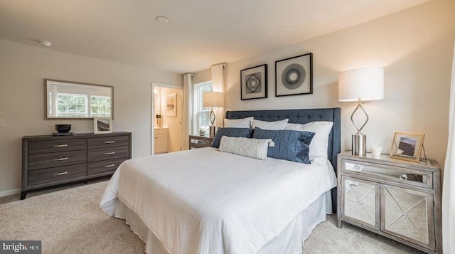 bedroom featuring ensuite bathroom and light carpet