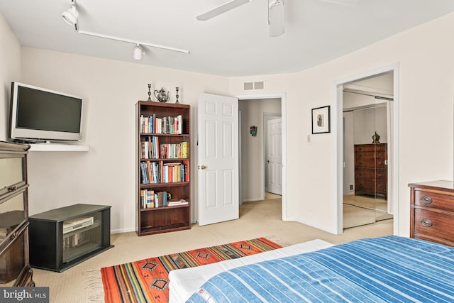 carpeted bedroom featuring rail lighting, a closet, and ceiling fan