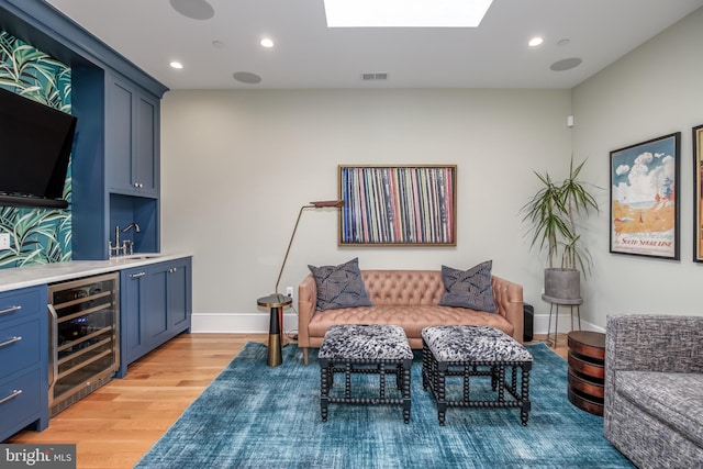 interior space with light hardwood / wood-style floors, beverage cooler, and indoor wet bar