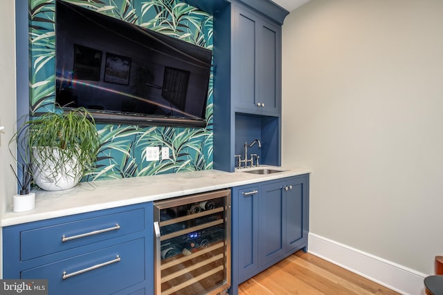 bar with blue cabinetry, light hardwood / wood-style floors, sink, and wine cooler