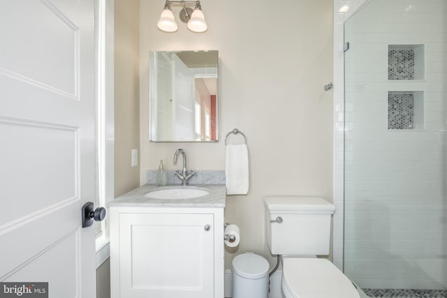 bathroom with a tile shower, vanity, and toilet