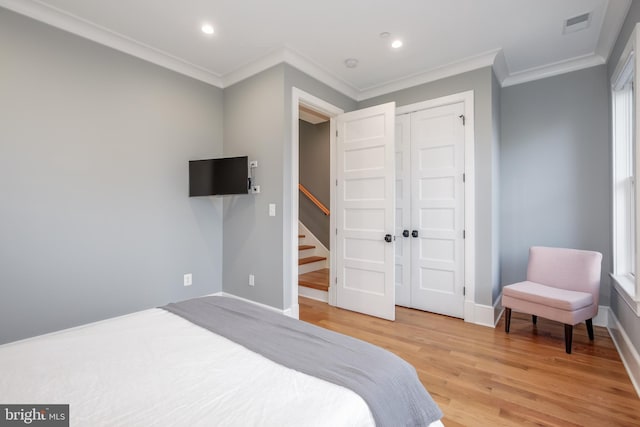 bedroom with hardwood / wood-style flooring, a closet, and crown molding