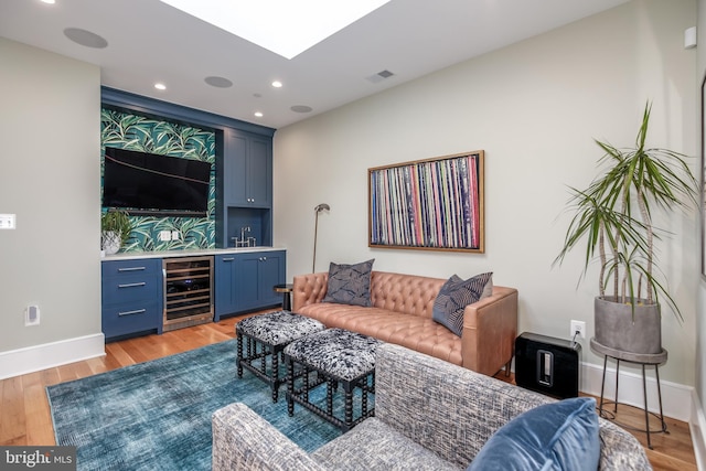 living room with indoor bar, wine cooler, and light hardwood / wood-style flooring