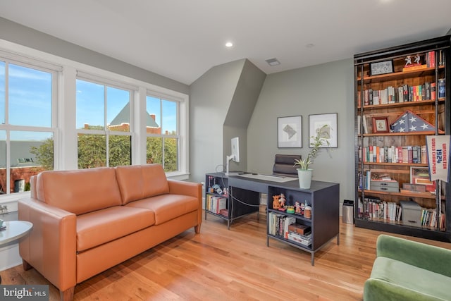 home office with light wood-type flooring and vaulted ceiling