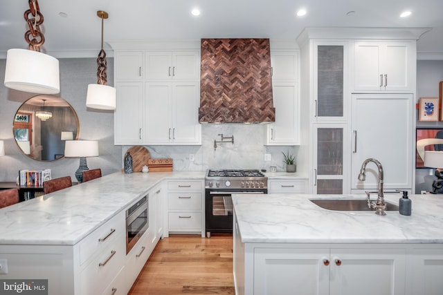 kitchen featuring sink, hanging light fixtures, light wood-type flooring, white cabinetry, and stainless steel appliances