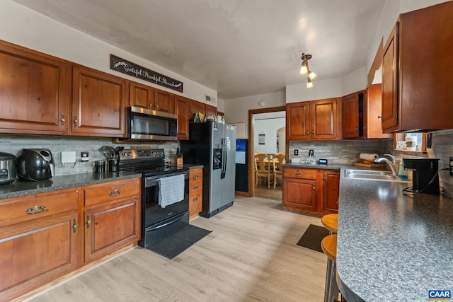 kitchen featuring light wood-type flooring, stainless steel appliances, tasteful backsplash, and sink