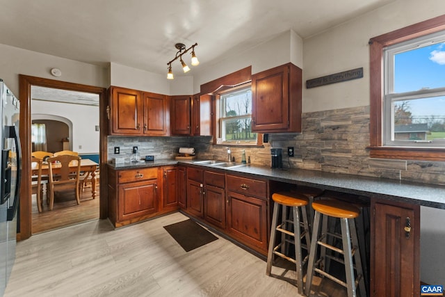 kitchen featuring decorative backsplash, light hardwood / wood-style floors, sink, and a breakfast bar