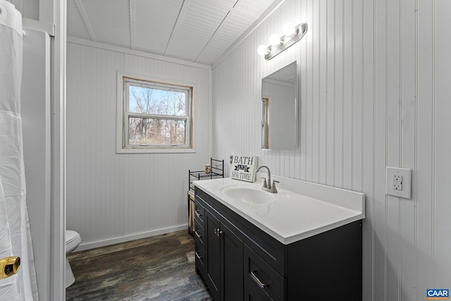 bathroom with vanity, hardwood / wood-style flooring, toilet, and wooden walls