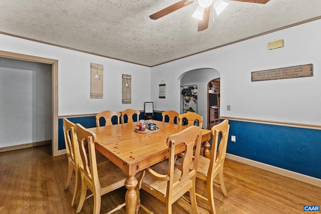 dining area with ceiling fan, wood-type flooring, and a textured ceiling