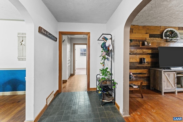 corridor with wood walls, dark hardwood / wood-style flooring, and a textured ceiling