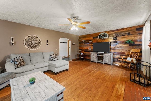 living room featuring hardwood / wood-style floors, wood walls, and a textured ceiling