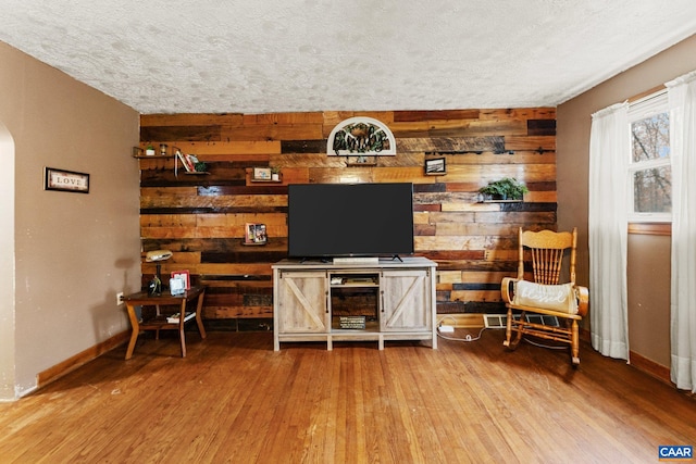 interior space with wood walls, wood-type flooring, and a textured ceiling