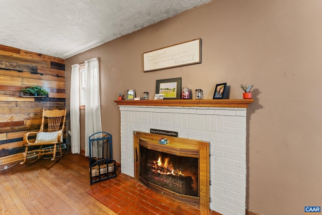 interior space with hardwood / wood-style floors, wood walls, a fireplace, and a textured ceiling