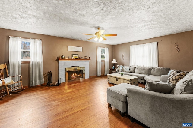 living room featuring a textured ceiling, plenty of natural light, wood-type flooring, and a fireplace