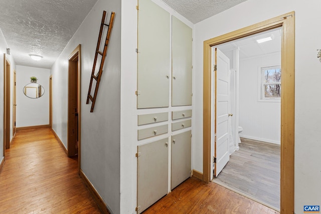 hall featuring a textured ceiling and light wood-type flooring