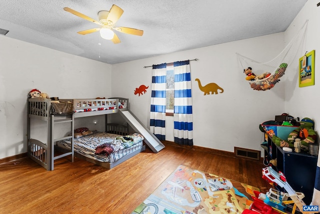 bedroom with ceiling fan, wood-type flooring, and a textured ceiling