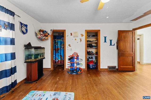 game room featuring hardwood / wood-style floors, a textured ceiling, and ceiling fan