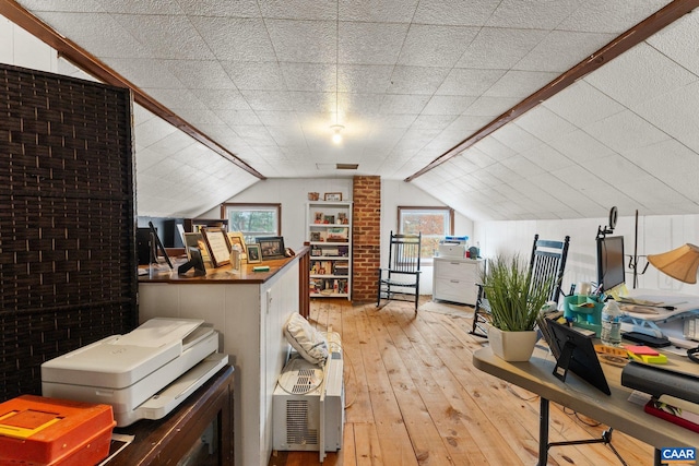 additional living space featuring lofted ceiling, light wood-type flooring, and brick wall