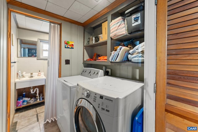 laundry area featuring washing machine and clothes dryer, crown molding, and light tile patterned floors