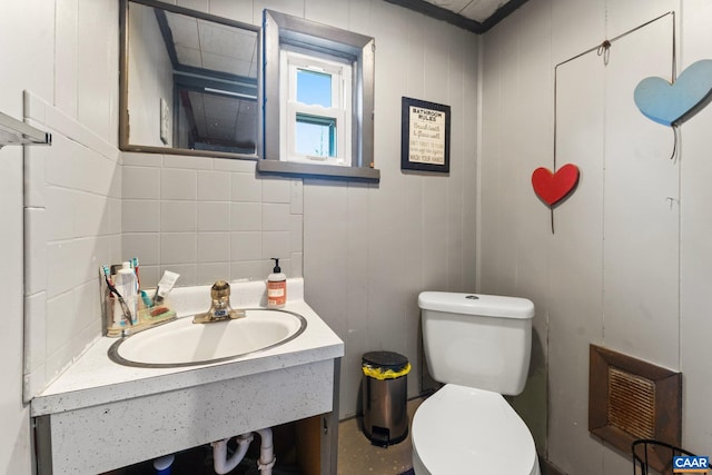 bathroom with wood walls, toilet, and sink