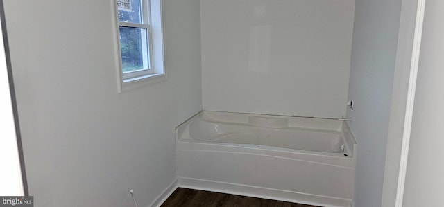 bathroom with hardwood / wood-style flooring and a bath