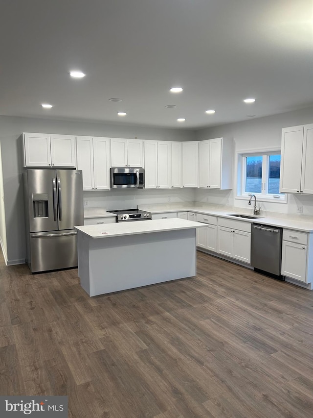 kitchen featuring a kitchen island, appliances with stainless steel finishes, white cabinetry, sink, and dark wood-type flooring