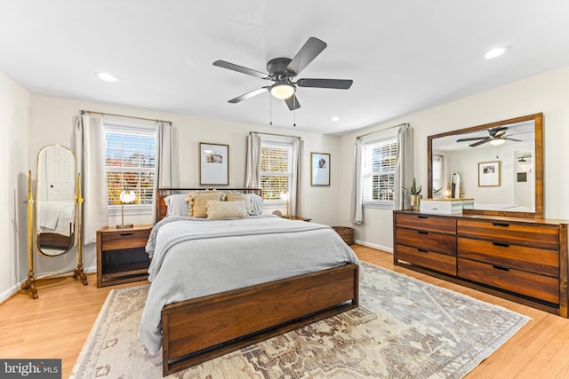 bedroom featuring ceiling fan, light hardwood / wood-style flooring, and multiple windows