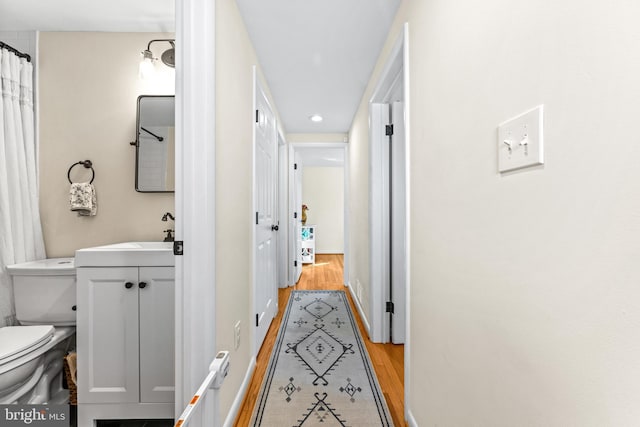 corridor with sink and light hardwood / wood-style flooring