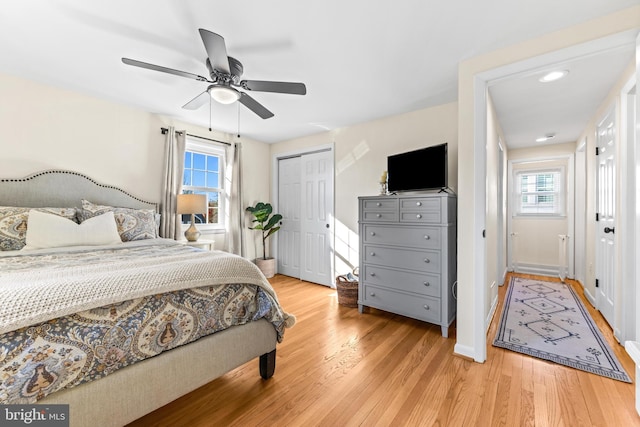 bedroom featuring ceiling fan, multiple windows, and light hardwood / wood-style flooring