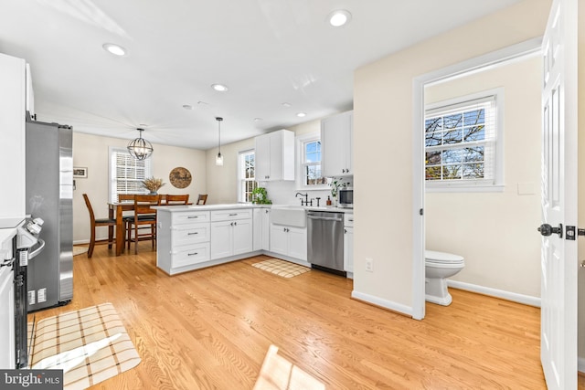 kitchen with decorative light fixtures, a healthy amount of sunlight, white cabinetry, and appliances with stainless steel finishes