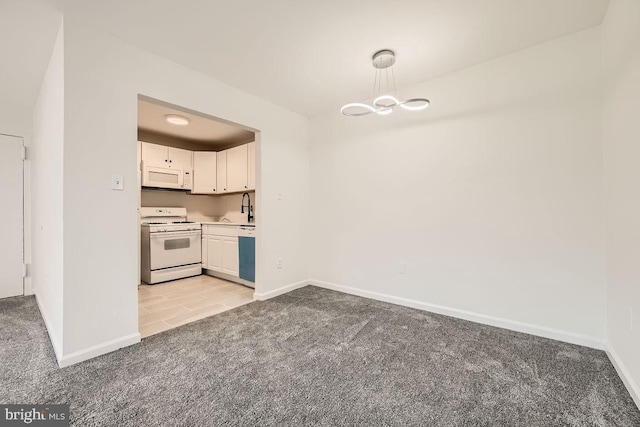 kitchen featuring white appliances, light colored carpet, and white cabinetry