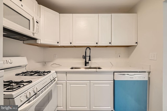 kitchen with white appliances, white cabinetry, and sink