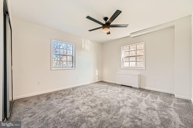 spare room with carpet, ceiling fan, radiator, and a wealth of natural light