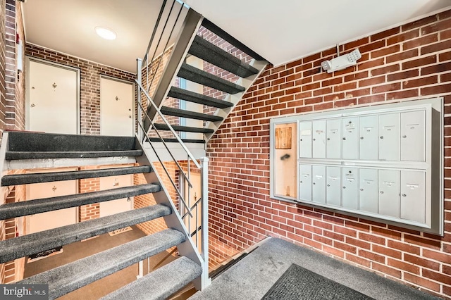 stairs with a mail area and brick wall