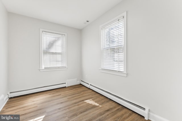 unfurnished room with light hardwood / wood-style floors and a baseboard heating unit