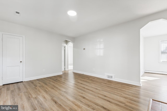 unfurnished room featuring a baseboard radiator and light hardwood / wood-style flooring