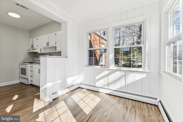 unfurnished dining area featuring hardwood / wood-style floors, crown molding, and baseboard heating