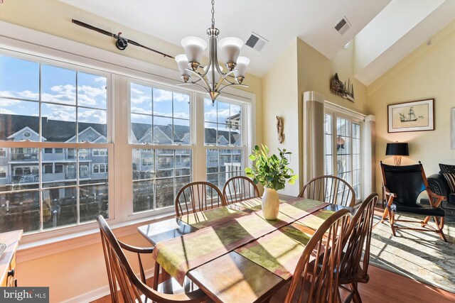 dining room with a chandelier, a mountain view, hardwood / wood-style flooring, and lofted ceiling