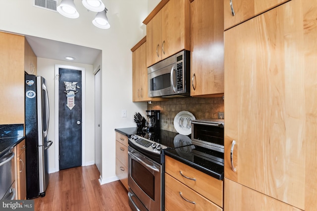 kitchen with hardwood / wood-style floors, backsplash, and appliances with stainless steel finishes