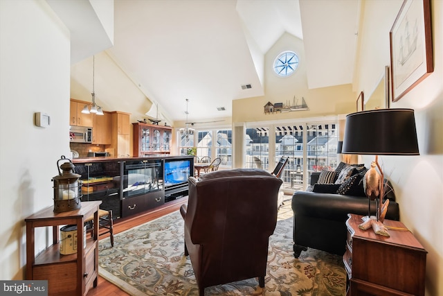 living room with high vaulted ceiling, light hardwood / wood-style floors, and an inviting chandelier