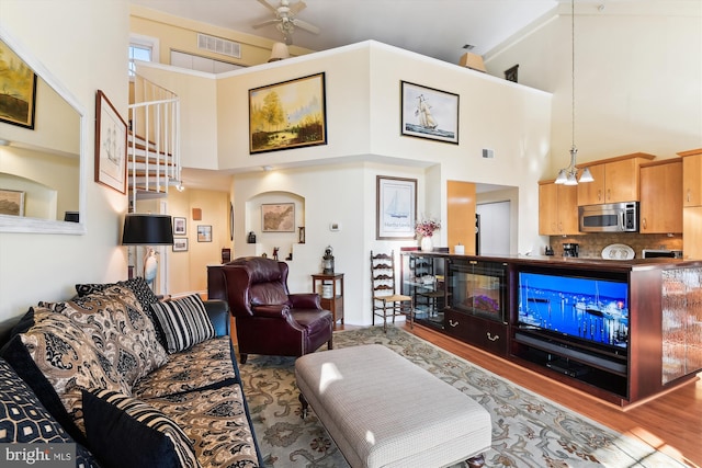 living room featuring hardwood / wood-style floors, ceiling fan, and high vaulted ceiling