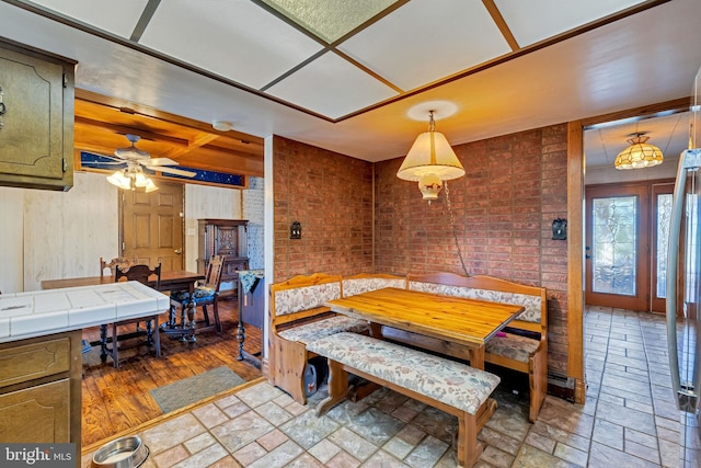 dining space featuring ceiling fan, brick wall, coffered ceiling, and wood-type flooring