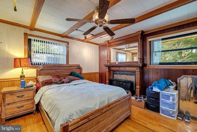 bedroom with wood walls, ceiling fan, light hardwood / wood-style floors, and crown molding