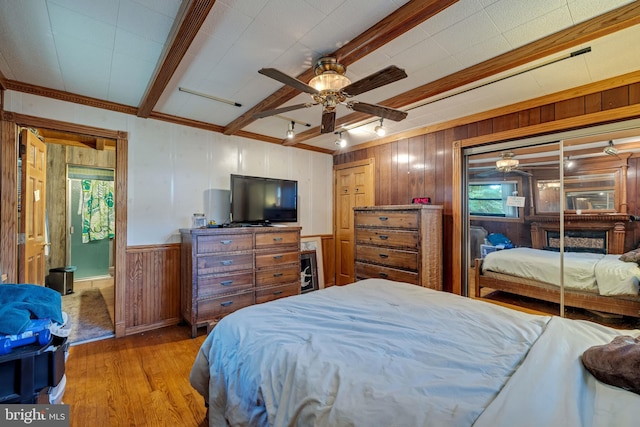 bedroom with ceiling fan, light hardwood / wood-style flooring, crown molding, and wood walls