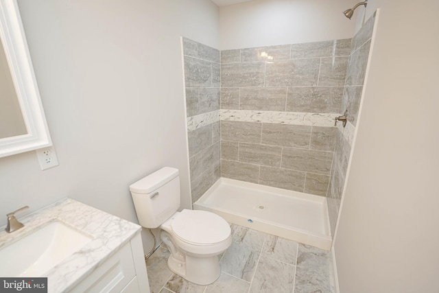 bathroom with vanity, toilet, and tiled shower