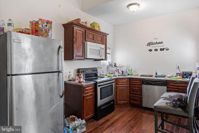 kitchen featuring light stone countertops, stainless steel appliances, and dark hardwood / wood-style floors